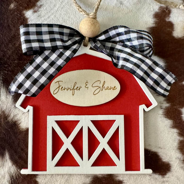 Red barn-shaped ornament with a checkered bow on a fur background