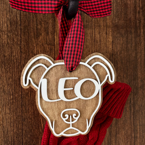 Wooden Pitbull dog-shaped ornament with personalized name on a red Christmas stocking against a wooden background