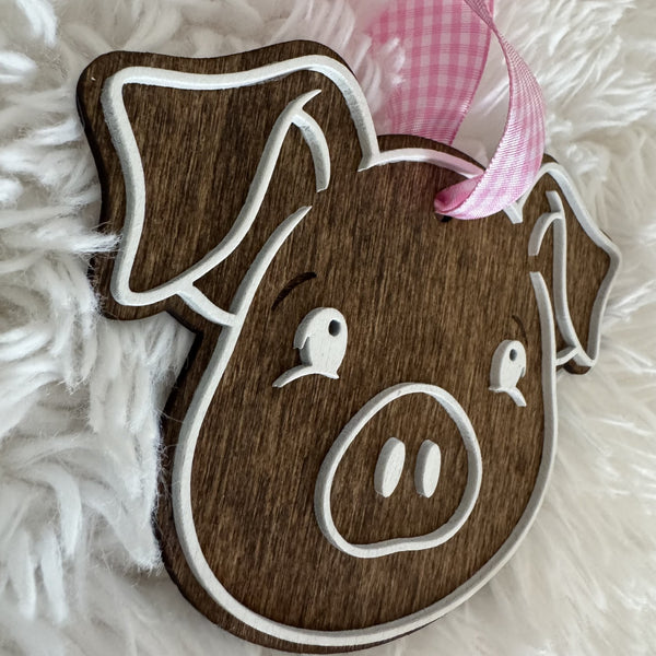 Side view of layered wooden pig ornament showing raised white details and rustic wood finish