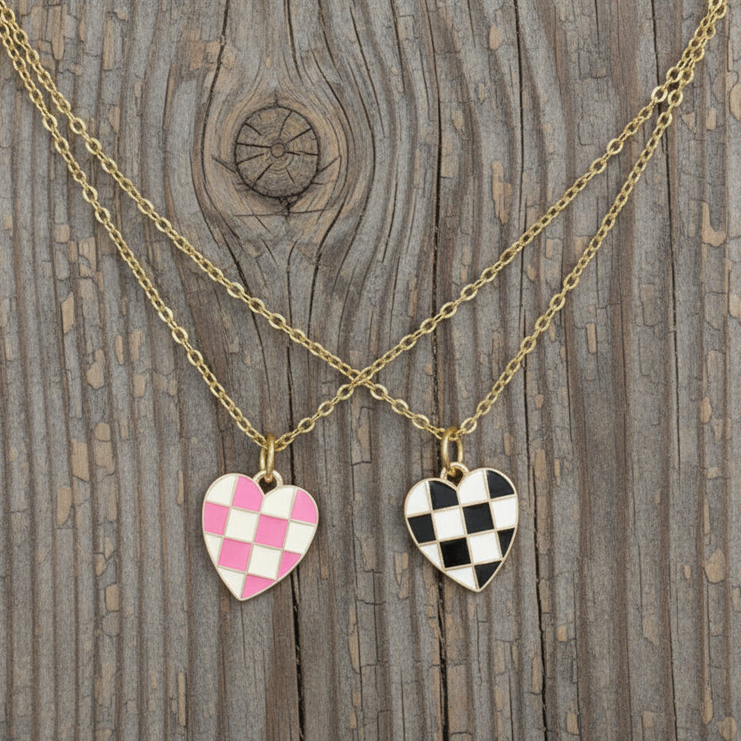 Two checkered heart charm necklaces on gold-tone chain with a wooden background