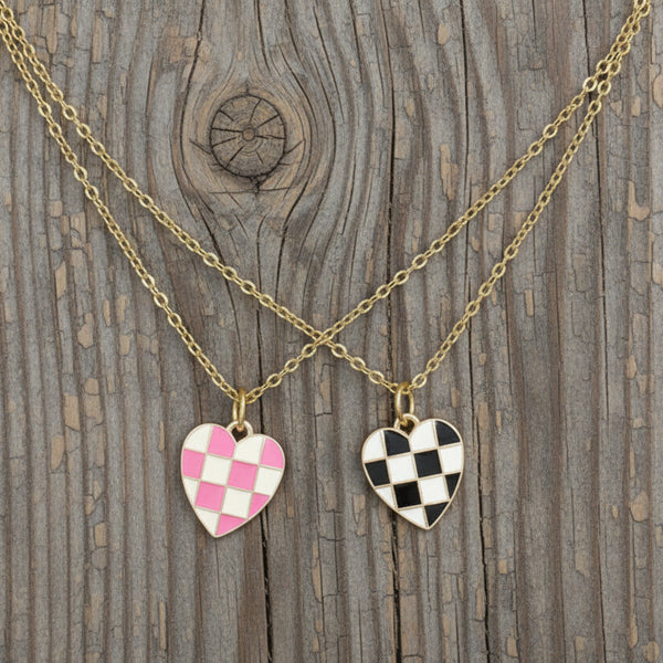 Two checkered heart charm necklaces on gold-tone chain with a wooden background