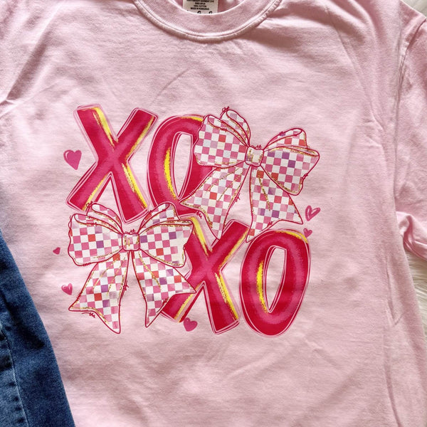 Pink t-shirt with 'XO' and checkered bows design on a plain background