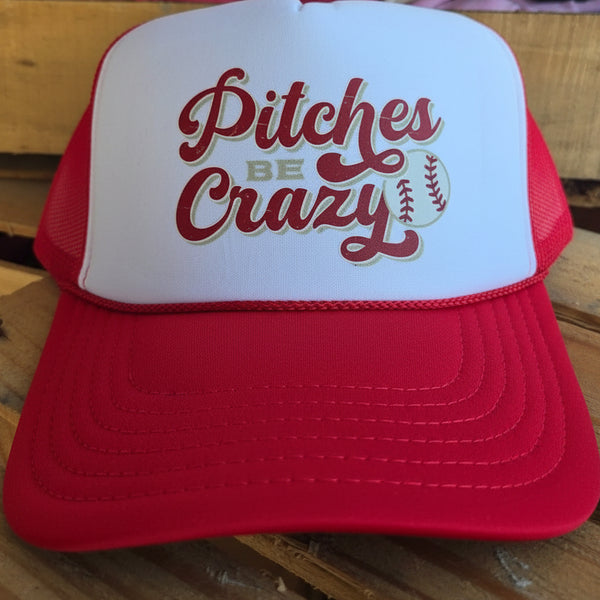 Red and white cap with 'Pitches Be Crazy' text on a wooden surface