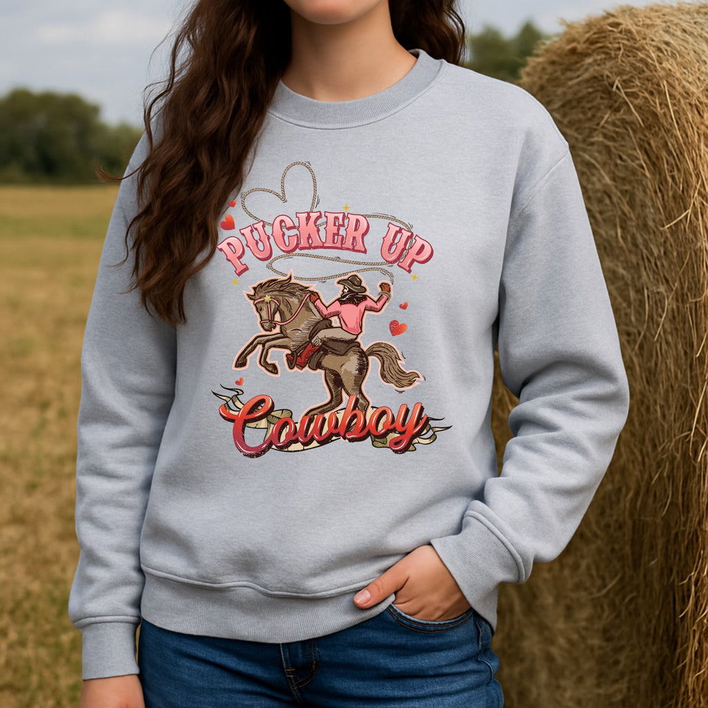 Person wearing a gray Valentine's Day sweatshirt with a cowboy graphic and text in an outdoor setting.