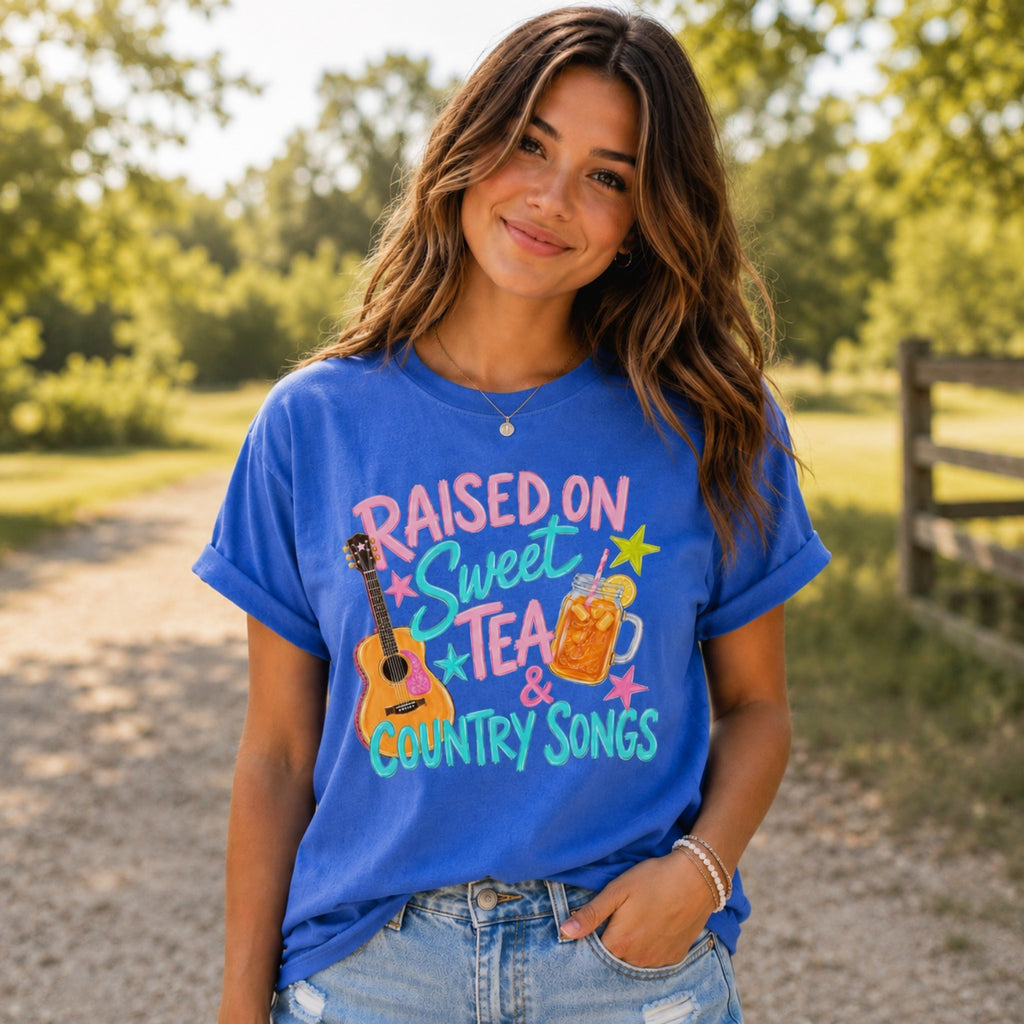 Young woman wearing Raised On Sweet Tea & Country Songs Comfort Colors graphic tee standing outdoors on a sunny country path
