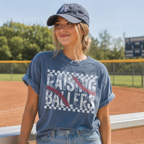Woman wearing a blue t-shirt with 'Raising Ballers' text on a baseball field