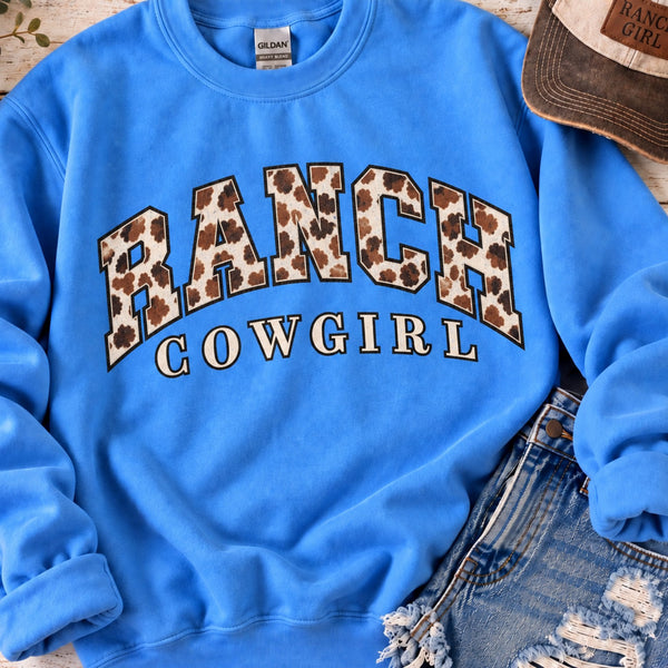 Blue Ranch Cowgirl crewneck sweatshirt with cow print varsity lettering styled with distressed denim and ranch girl hat