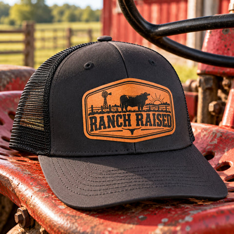 Youth Ranch Raised cattle trucker hat displayed on a vintage red tractor