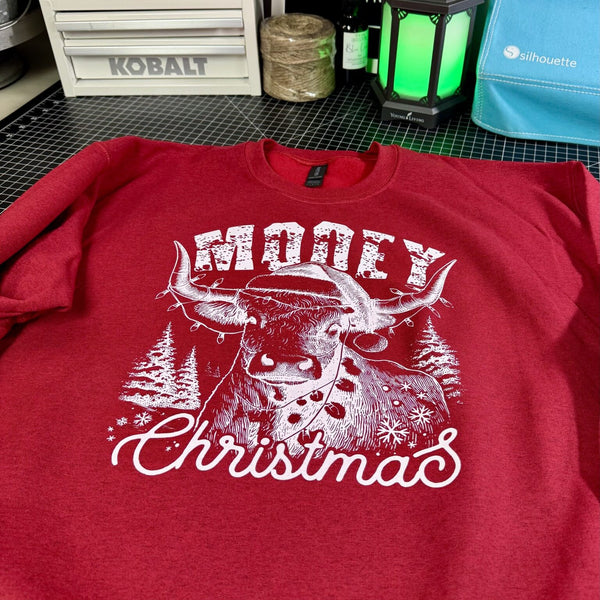 Red sweatshirt with a white bull graphic and 'Merry Christmas' text on a workshop table.