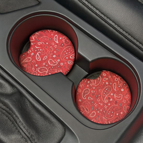 Red paisley patterned car coasters in a cup holder.