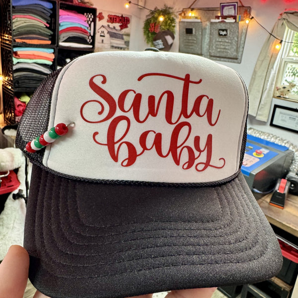 Santa Baby Christmas trucker hat with red script lettering on black and white foam mesh cap
