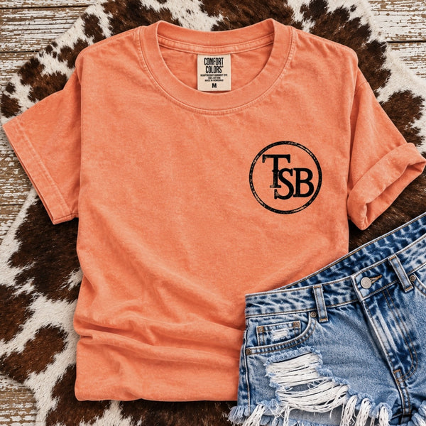 Comfort Colors Neon Cantaloupe graphic tee with small black TSB cattle brand left chest design