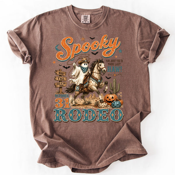 Spooky Rodeo Halloween western graphic tee on a Comfort Colors Espresso shirt featuring a ghost cowboy riding a horse with pumpkins, cactus, and vintage retro country artwork.