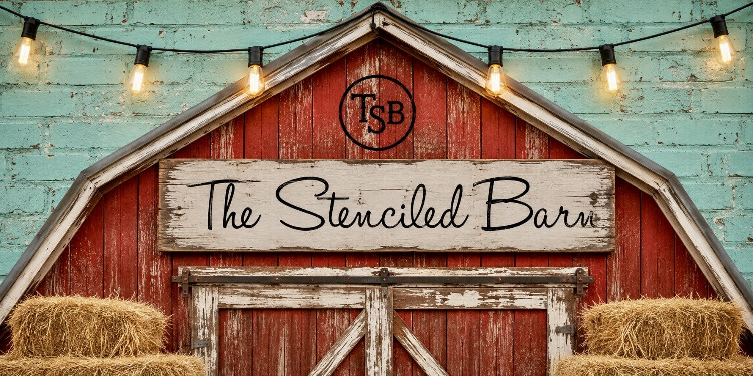 The Stenciled Barn branded red barn with TSB cattle brand logo, antique white sign, aqua brick wall, rustic string lights, and hay bales.