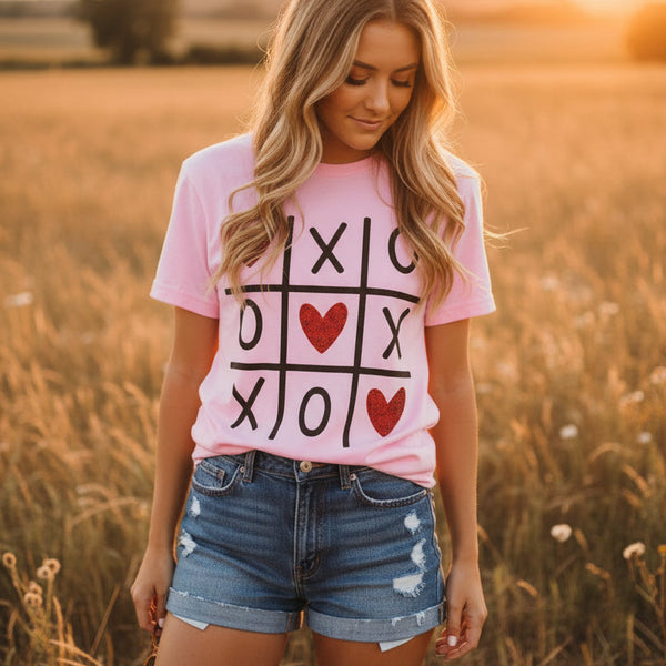 Woman wearing a pink t-shirt with a tic-tac-toe design in a field