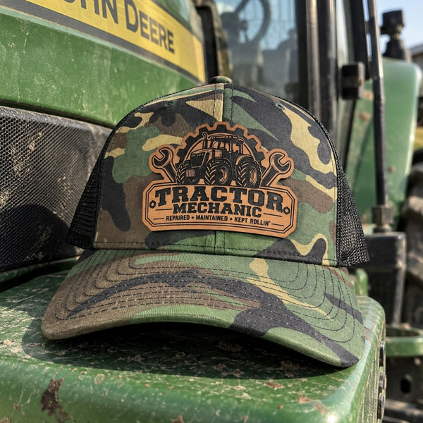 Tractor Mechanic camo Richardson 112 leather patch hat displayed on a farm tractor