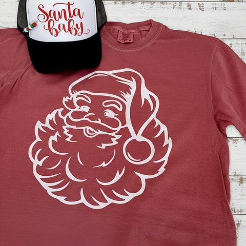 Red t-shirt with white Santa Claus graphic and a black cap with 'Santa baby' text on a light background.