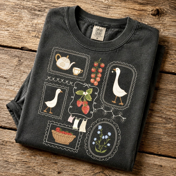 Vintage goose and strawberry graphic printed on a Comfort Colors Pepper t-shirt displayed flat with distressed denim shorts on a rustic wooden background.