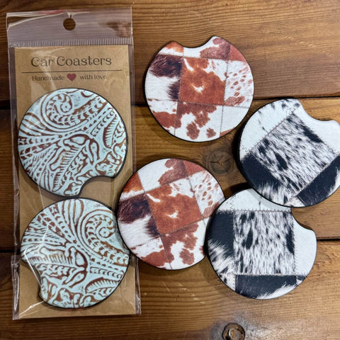 Western neoprene car coasters in turquoise tooled, brown cowhide, and black white cowhide patterns on rustic wood background