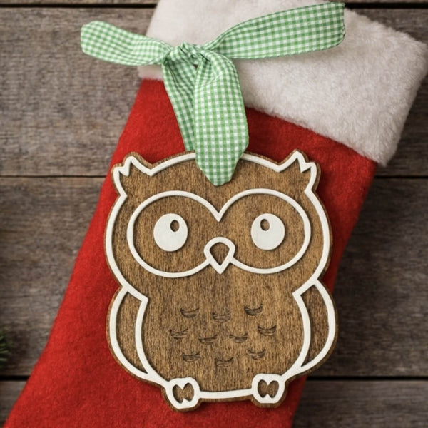 Red Christmas stocking with a wooden owl ornament and green ribbon on a wooden background