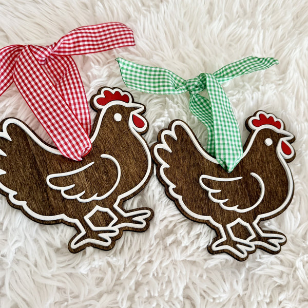 Two rustic wooden hen Christmas ornaments with dark wood finish, raised white details, red accents and gingham ribbons.