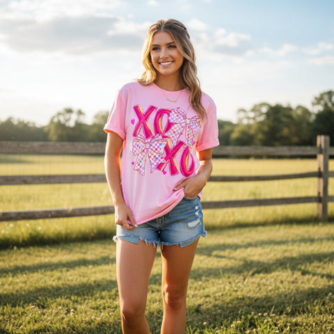 Woman wearing a pink t-shirt with 'XO XO' Valentine's Day design in a field